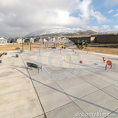 Square Park and childrens playground against homes and snow capped mountain in winter Stock Photo