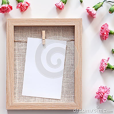A square photo of a wooden mockup frame with a natural jute filling surrounded by pink flowers Stock Photo