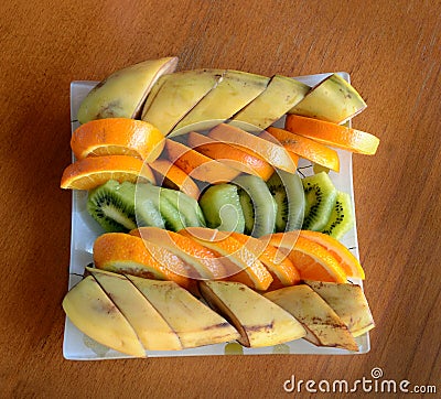 In a square plate sliced tropical fruits - bananas, kiwi, orange Stock Photo