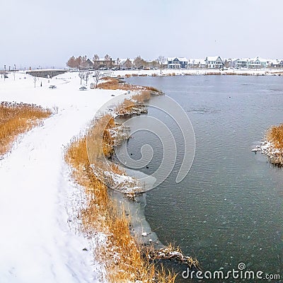 Square Snowy bridge overlooking a calm silvery lake amid a frosty landscape in winter Stock Photo