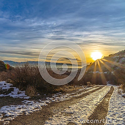 Square Snowy dirt road in Provo Canyon overlooking lake mountain and sun at sunset Stock Photo