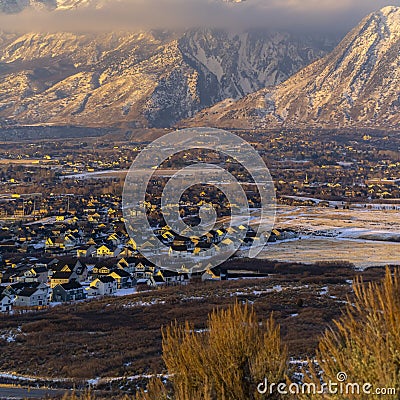 Square Snowy Mount Timpanogos and charming homes against cloudy blue sky at sunset Stock Photo