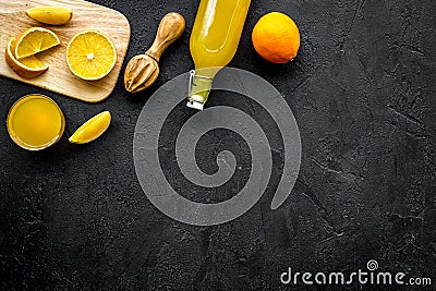 Squeeze juice from oranges. Juicer, slices of oranges, beverage in glass and bottle on black background top view copy Stock Photo