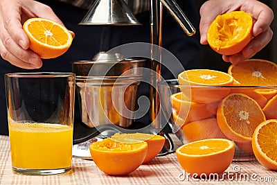 Squeezing an orange with a manual press, close view, making a glass of fresh. Fresh oranges on a wooden table, whole, squeezed and Stock Photo