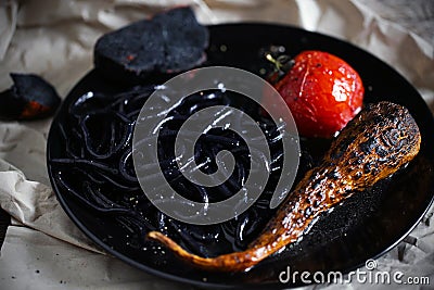 Squid ink black colored noodles with char-grilled tomato, creative Stock Photo