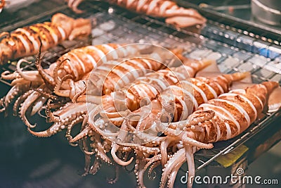 Squid on skewers is being grilled by a street vendor Stock Photo