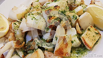 Squid in small pieces cooked in a pan and seasoned with lemon slices Stock Photo