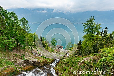 St. Beatus Cave and waterfalls above Thunersee, Sundlauenen, Switzerland. Falls are running down the mountain with a green grass Stock Photo