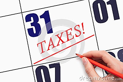 31st day of the month. Hand writing text TAXES and drawing a line on calendar date Stock Photo