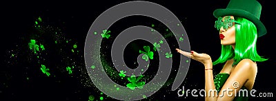 St. Patrick`s Day leprechaun model girl pointing hand, holding product, isolated on black magic background, blowing shamrock leave Stock Photo