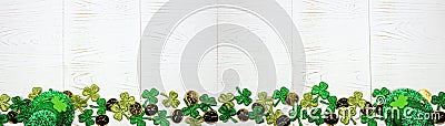 St Patricks Day banner with bottom border of green shamrocks, gold coins and leprechaun hat, overhead view over a white wood backg Stock Photo