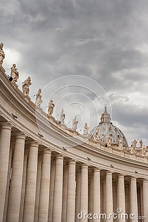 St. Peter`s Basilica, Group of statues of Peter`s Square Colonnade with rainy clouds on background, Vatican city state Editorial Stock Photo