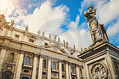 St. Peter`s square, Vatican City, Roma. Low angle view of the statue of St. Peter with the front of the Basilica in the background Editorial Stock Photo