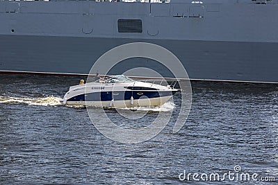 A pleasure boat sails alongside a warship on the Neva in St. Petersburg Editorial Stock Photo