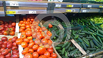 Rows of shelves with red tomatoes and green cucumbers in local farmers market or supermarket. Fresh vegetables. Rich harvest. Supp Editorial Stock Photo