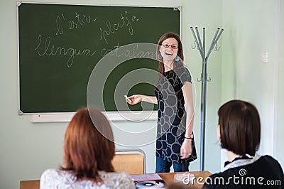 Spanish teacher, young attractive girl at the blackboard explains the learning material to Editorial Stock Photo