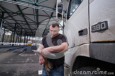 Truck driver with a package of declarations at customs Editorial Stock Photo