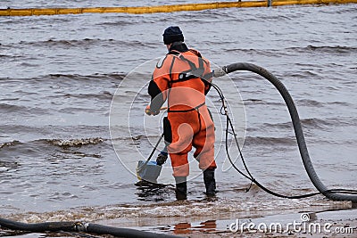 Employees of the environmental service clean up after low tide on the coast Gulf of Finland remove garbage, oil spills, harmful Editorial Stock Photo