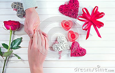 St. Valentine`s Day, Love concept. Young couple taking hands, over holiday decorated wooden background. Top view Stock Photo