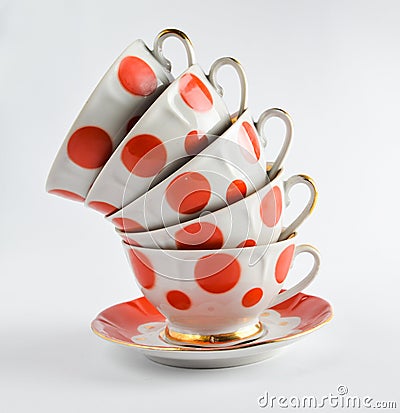 A stack of antique ceramic cups on a saucer on a white background. Stock Photo