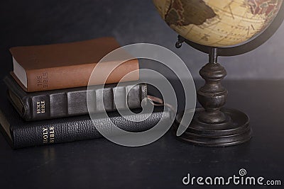 Stack of Bibles and a Globe on a Dark Background Stock Photo