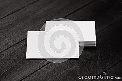 Stack blank corporate identity business cards on black stylish wood background with blur, mock up. Stock Photo