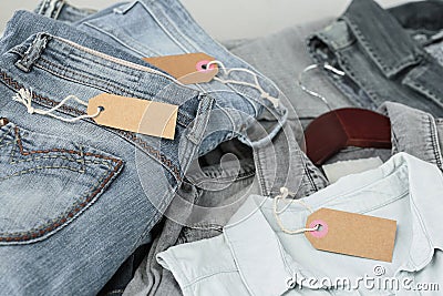 Stack of blue jeans, shirts and empty tag. Second hand clothing shop Stock Photo