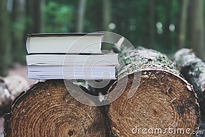 A stack of books lying on felled trees, save trees - read ebook Stock Photo