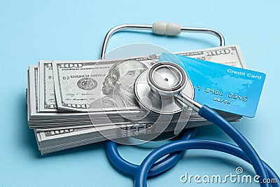 Stack of cash dollars and credit card with stethoscope on blue background. The concept of medical strechevka or expensive medicine Stock Photo