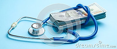 Stack of cash dollars and stethoscope on blue background. The concept of medical strechevka or expensive medicine, doctors salary Stock Photo