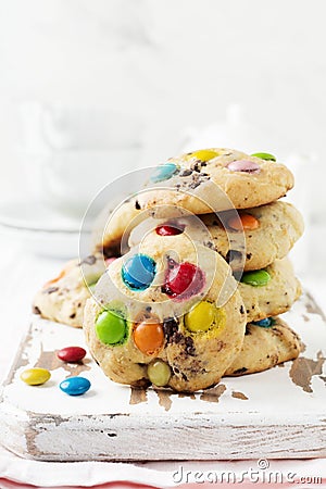 Stack of children cookies with colorful chocolate candies in a sugar glaze on a white light wooden background. Selective focus Stock Photo