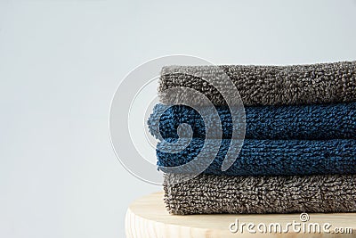 Stack of clean folded navy blue beige terry towels on wooden char gray wall background. Laundry spa wellness cleanliness concept Stock Photo