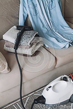 A stack of clean warm clothes and shirt with a steam cleaner on Stock Photo