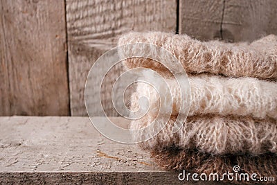 Stack of clothes from knitted knitwear on a wooden background, copy space. Autumn fall winter homely concept. Stock Photo