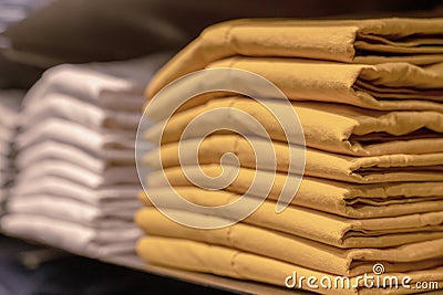 A stack of clothes in the store, pullovers and sweatshirts nicely and neatly stacked in bundles on the table, yellow Stock Photo
