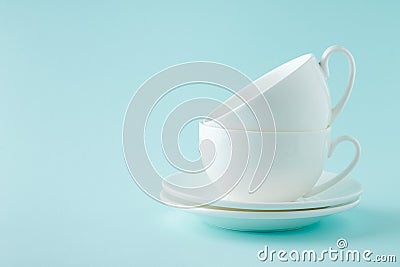 Stack coffee or tea white cups with saucers on cyan background. Stock Photo