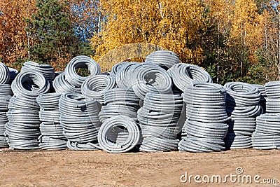 Stack of coiled plastic pvc Polyethylene Corrugated drainage pipes for sewer system outdoor warehouse Stock Photo