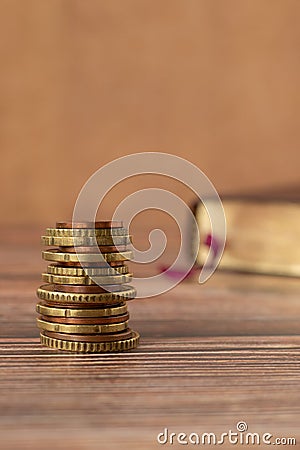 Stack of coins and holy bible book with golden pages on a wooden background, vertical shot, copy space Stock Photo