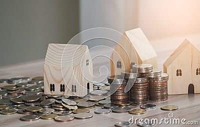 Stack of coins money with wood house model on table and sunlight, Business Growth concept, Financial risk. for plan saving money Stock Photo
