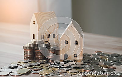 Stack of coins money with wood house model on table and sunlight, Business Growth concept, Financial risk. for plan saving money Stock Photo