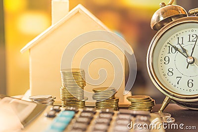 Stack of coins planing to buy home with clock and house model Stock Photo