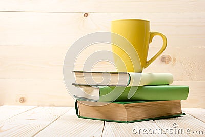 Stack of colorful books, open book and cup on wooden table. Back to school. Copy space Stock Photo