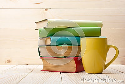 Stack of colorful books, open book and cup on wooden table. Back to school. Copy space Stock Photo