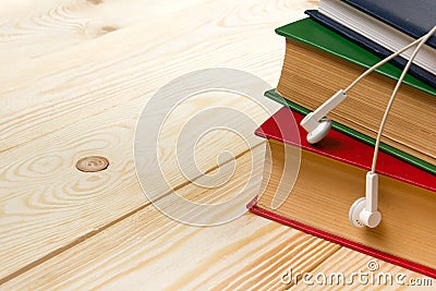 Stack of colorful books on wooden table and headphones. Audiobook concept Stock Photo