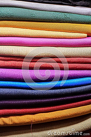 Stack of colorful fabrics layered horizontally, showcasing a variety of textures and patterns. Stock Photo