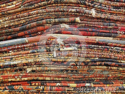 Stack of colorful handmade antique Oriental style rugs and carpets background texture pattern Stock Photo