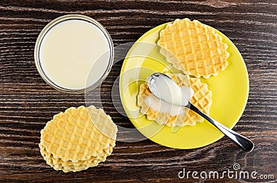 Stack of cookies, condensed milk in spoon on cookie in saucer, bowl with condensed milk on wooden table. Top view Stock Photo