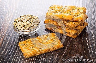 Stack of cookies with sunflower seeds, bowl with peeled seeds on wooden table Stock Photo