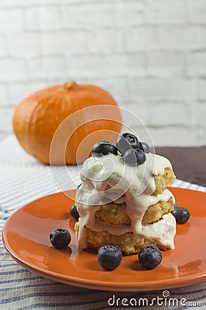 A stack of cottage cheese pancakes with sour cream and blueberries on an orange plate, side view Stock Photo