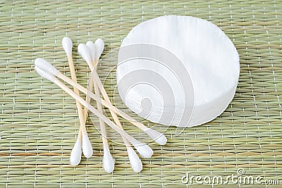 Stack of cotton pads and heap of wood stick cotton buds on a bast fiber mat background. Plastic free hygiene supplies, beauty Stock Photo